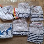 2.2 collection of folded, individually wrapped white short-sleeve polo shirts featuring various striped and patterned collar