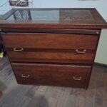 4 wooden two-drawer cabinet featuring a glass top display surface and brass-tone pull handles